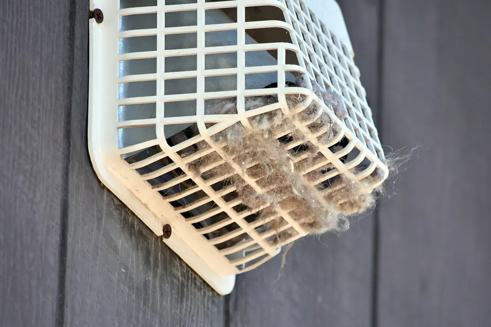 An outside dryer vent shown with considerable lint and debris which could cause a fire